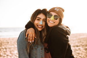 Two women wearing noz sunscreen, hugging each other and smiling